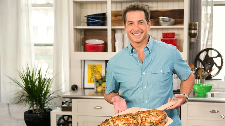 Bobby Deen smiles while displaying pizzas