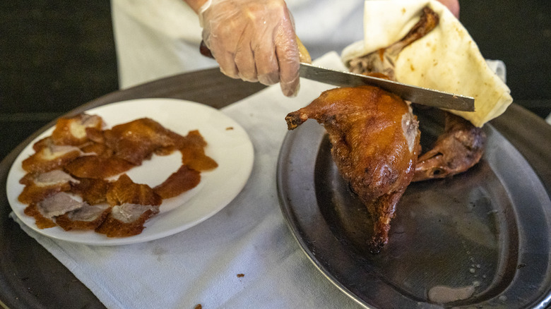 Restaurant worker cutting Peking duck