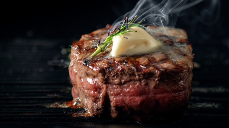 grilled beef tenderloin steak with butter and herb garnish