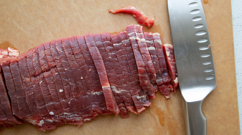 raw steak strips with knife