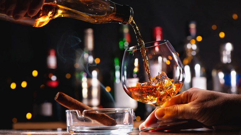 Person pouring whiskey into glass