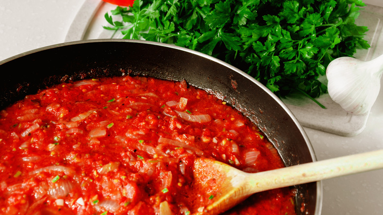 pot of tomato sauce with fresh parsley and garlic in frame