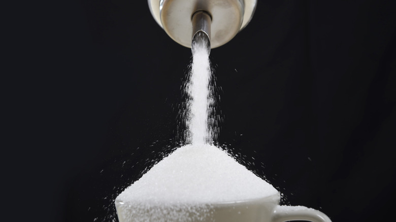 Pouring cupful of sugar