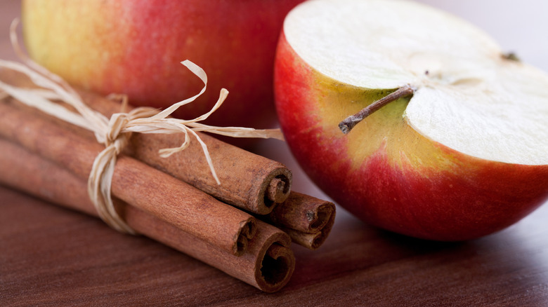 A cut apple and bundle of cinnamon sticks