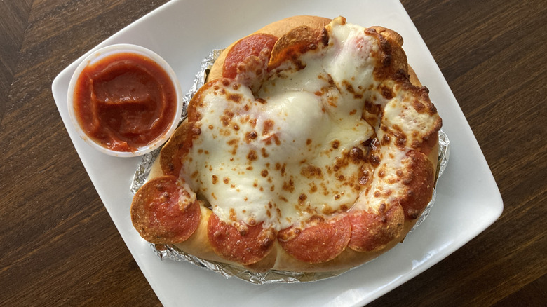 Sams Club pizza pretzel with sauce is displayed on a plate.