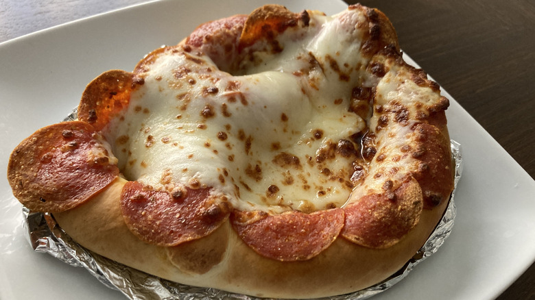 A pizza pretzel rests on a plate.