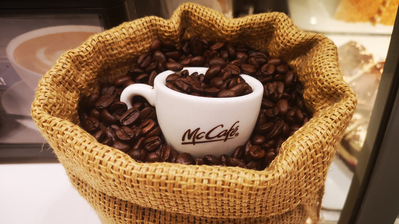 A white McCafe cup in a bag of coffee beans