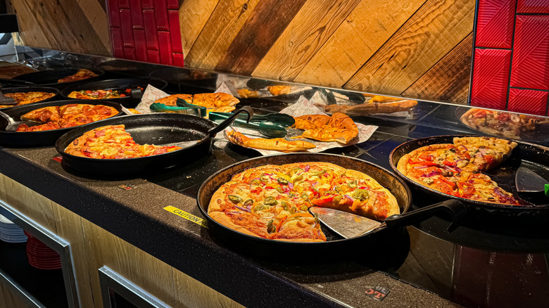 Pizzas in metal tins at Pizza Hut buffet