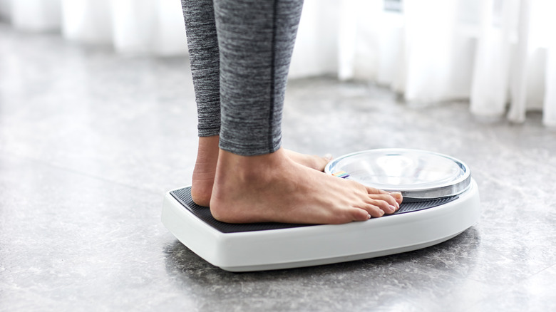 Woman weighing self at home