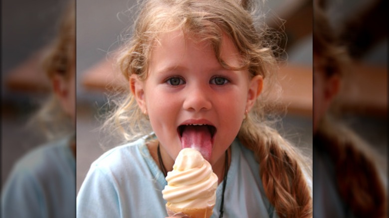 Young girl joyfully licking soft serve