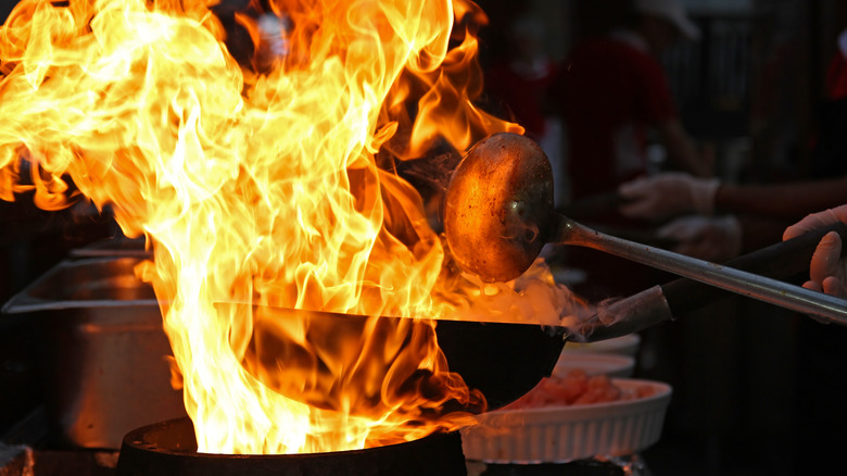 chef cooking over fiery wok