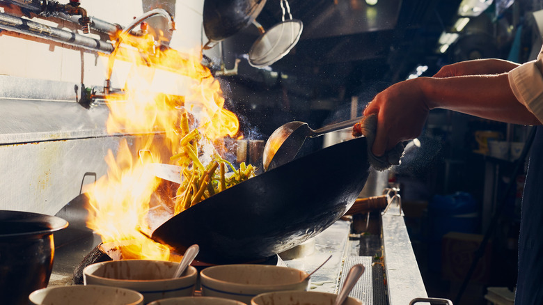 chef cooking ingredients in wok