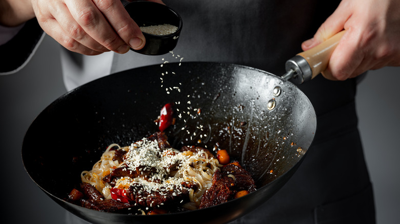 chef seasoning food in wok