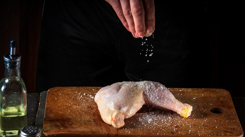 sprinkling salt on chicken leg