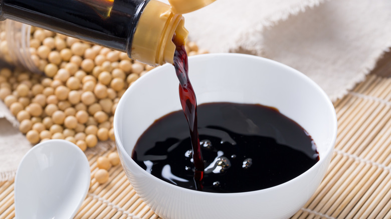 Soy sauce poured from a bottle into a bowl