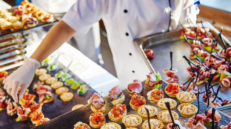 Person in white gloves plating dishes