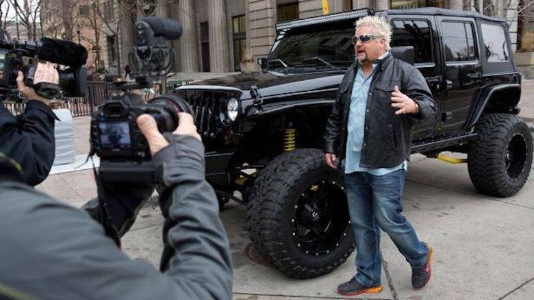 Guy Fieri being filmed in front of a jeep