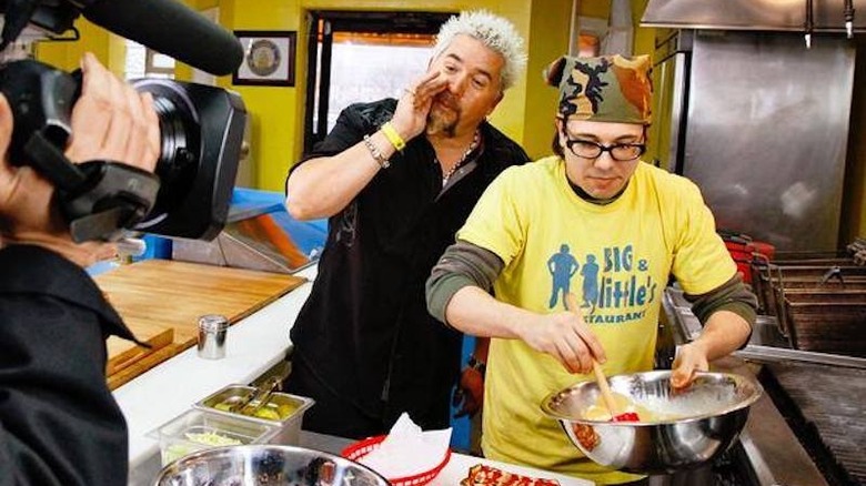 Guy Fieri behind a chef being filmed