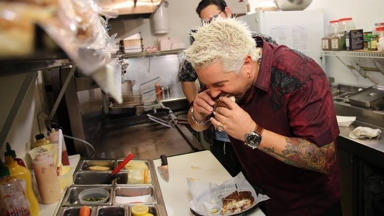 Guy Fieri taking a bite of a sandwich