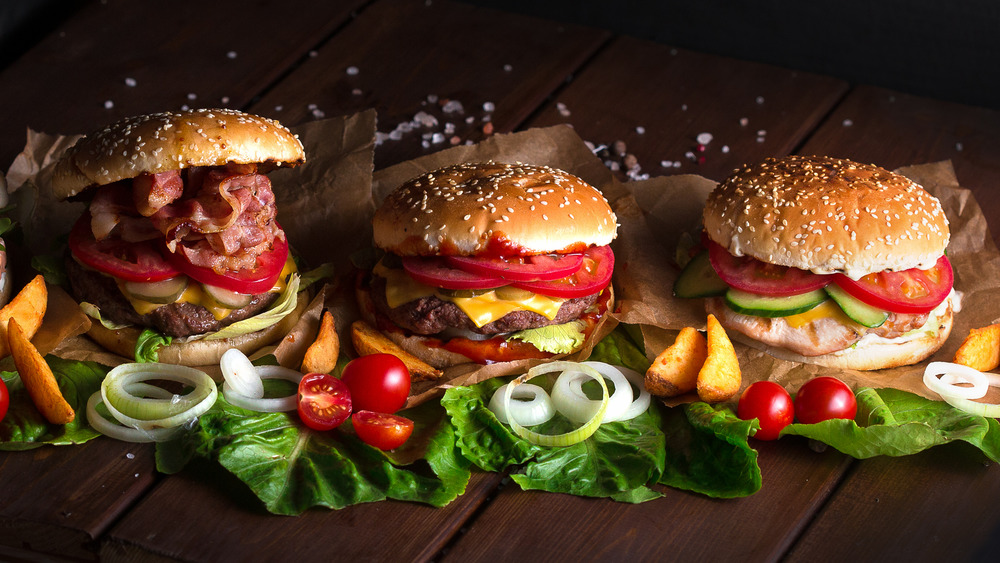 Three burgers with lots of condiments