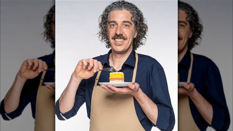 Giuseppe holding fork and plated cake with white background