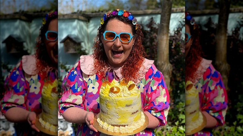 Lizzie holding a cake in a garden