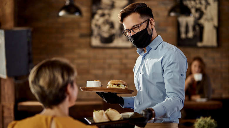 Waiter giving food to seated customer