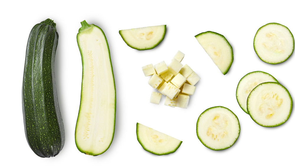 sliced and whole zucchini on a white background