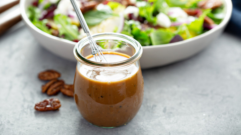 Glass of vinaigrette with tiny whisk