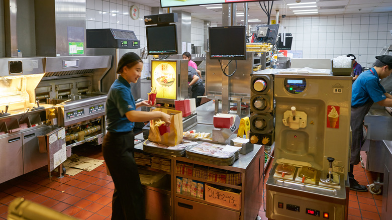 Mcdonald's employee in kitchen with french fries