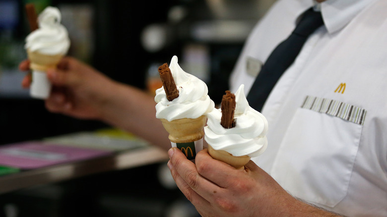 mcdonald's employee holding three ice cream cones