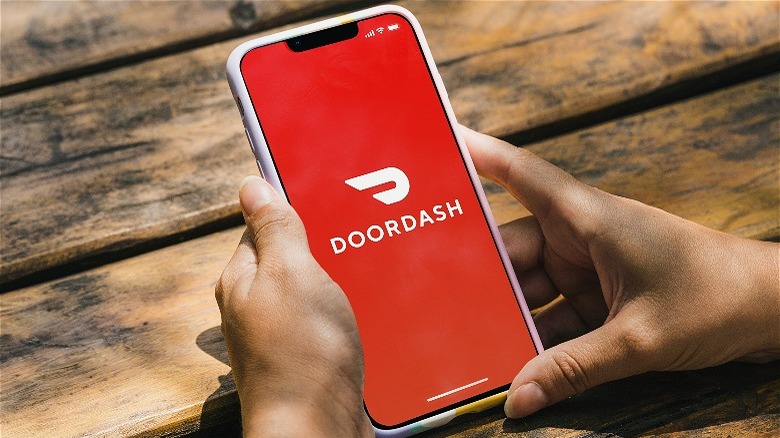 person holding phone with DoorDash logo