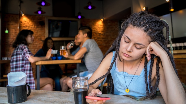 Girl alone while others drink