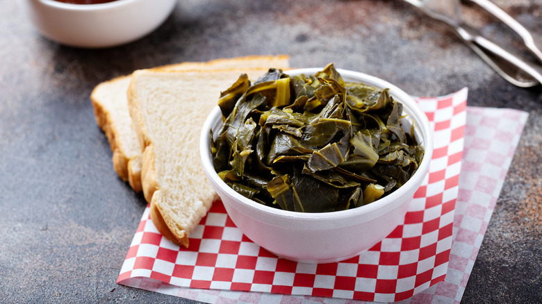 A bowl of cooked collard greens with bread