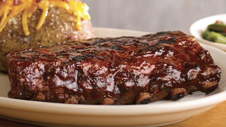 A rack of saucy ribs and a baked potato at Texas Roadhouse restaurant