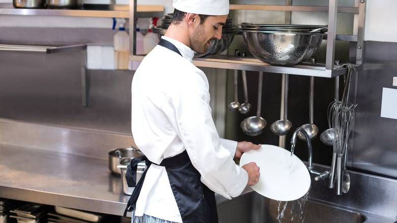 Chef washing a plate in a restaurant kitchen