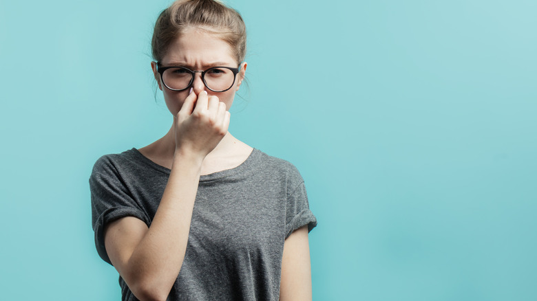 Woman blocks nose with fingers