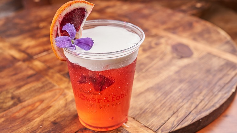 Plastic cup with red beverage and decorated with a flower