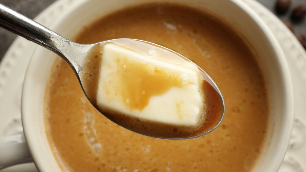 Spoonful of butter being stirred into coffee