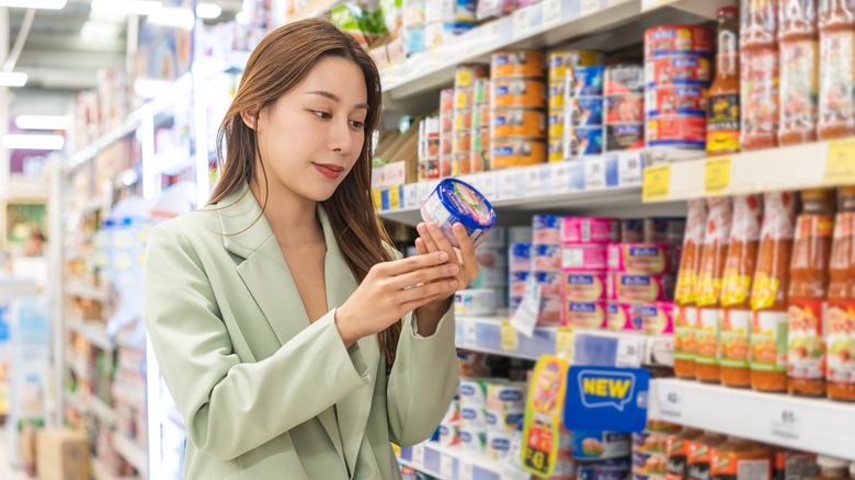 woman grocery store checking tuna can