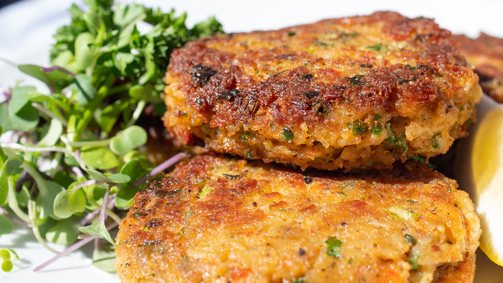 stack of crab cakes with side of greens