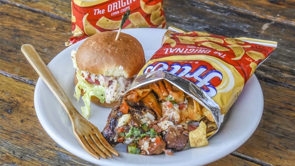 Fritos pie in a bag on a dish with a burger