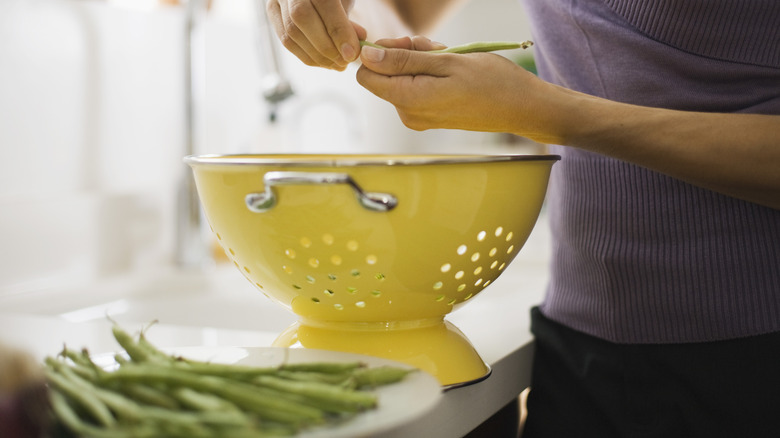 Woman snapping green beans colander