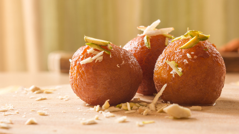 Three pieces of gulab jamun topped with nuts