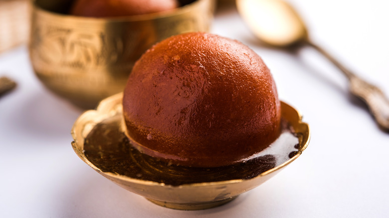 Single gulab jamun in gold dish 