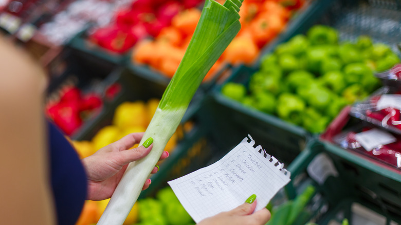 woman holding leek at supermarket