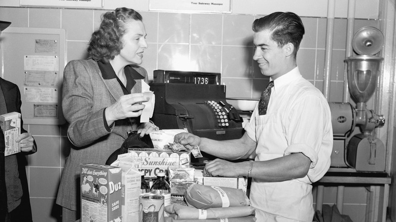 Woman purchasing groceries from male cashier