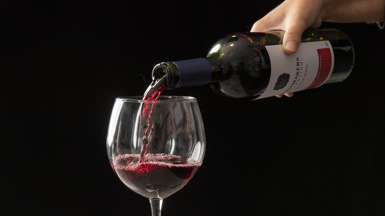 Pouring Cabernet Sauvignon into glass on dark background