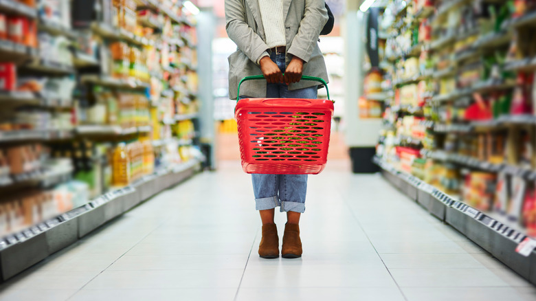 Woman with basket standing in grocery aisle