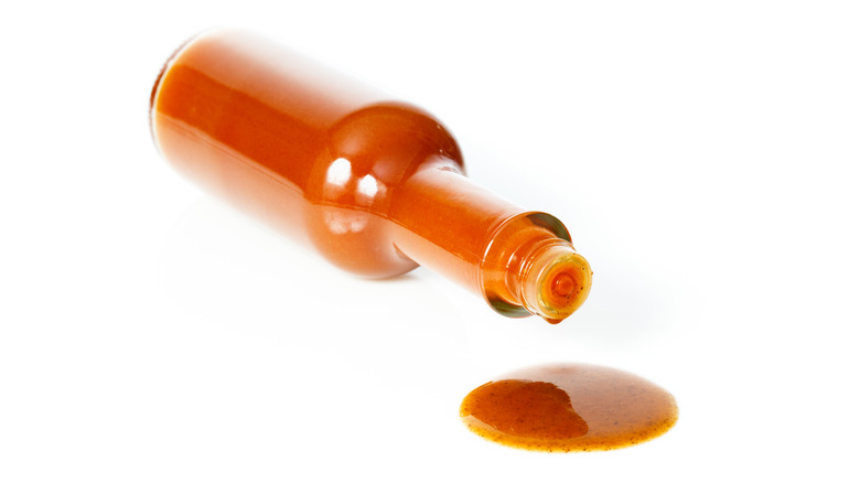 Bottle of hot sauce on its side dripping